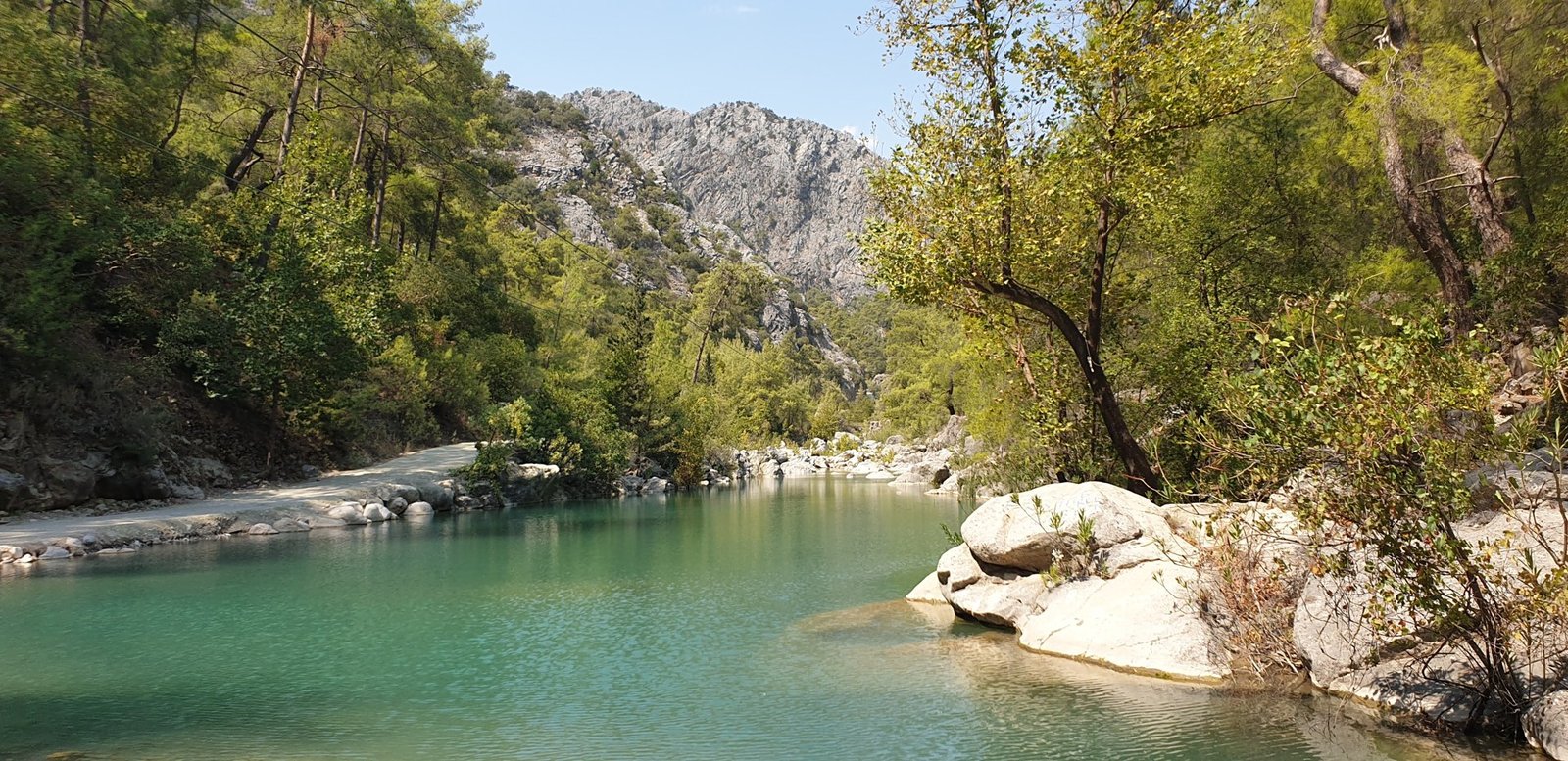 Turquoise-green water between rocks and wooded slopes in Göynük Canyon