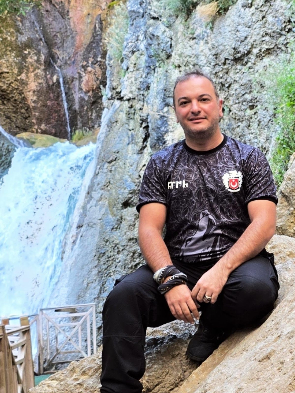 A pause along the way: Burak beside a waterfall. The exact location has not been confirmed.