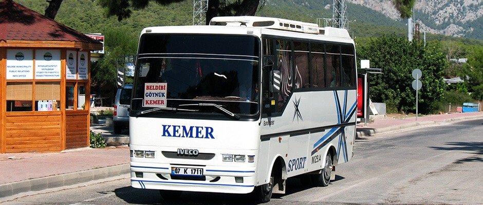 White bus displaying Kemer, with mountains in the background.