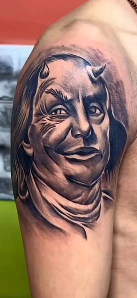 Black and grey portrait tattoo on an upper arm
